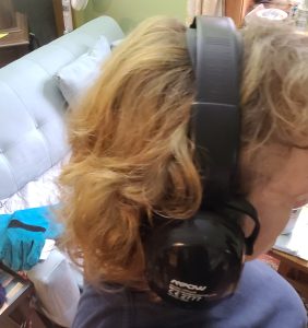 This image shows a woman wearing heavy duty ear defenders, with heavy-duty padded leather gloves within reach.